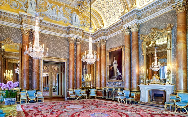 Blue Drawing Room at Buckingham Palace with chandeliers, ornate columns, and regal portraits.