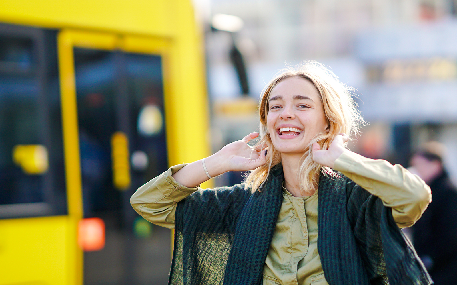 Woman smiling in front of a yellow tram.