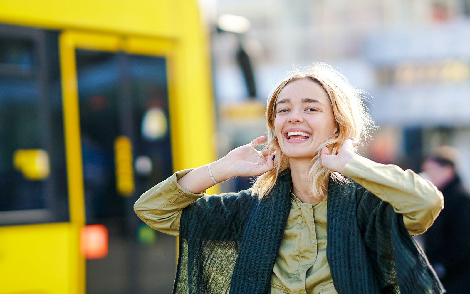 Woman smiling in front of a yellow tram.