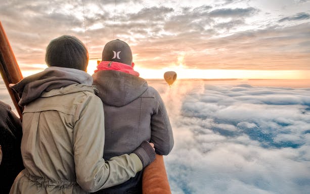 Couple enjoying sunrise view from hot air balloon over Avon Valley.