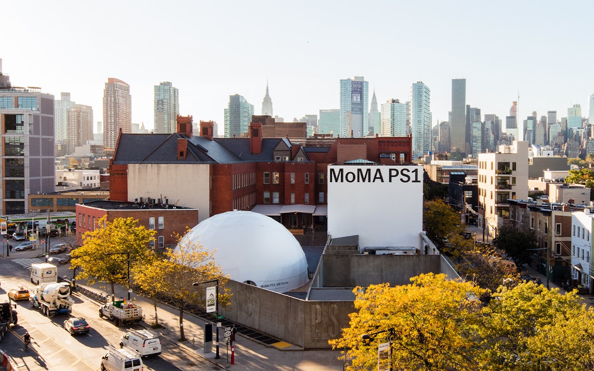 MoMA PS1 exterior with New York City skyline in the background.