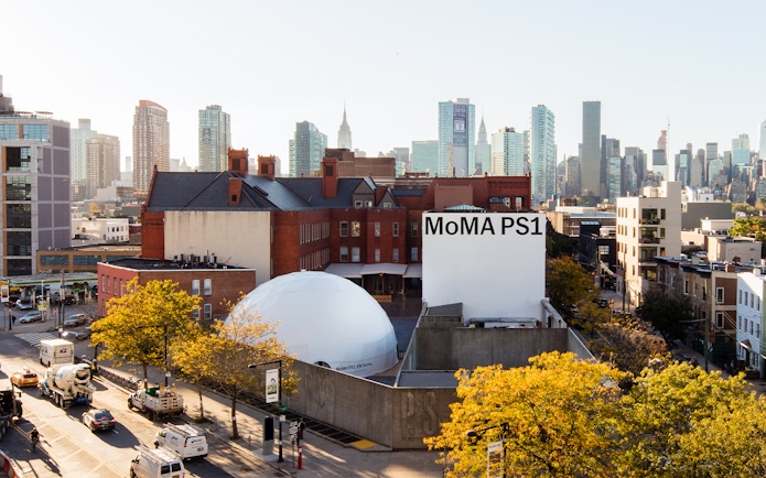 MoMA PS1 exterior with New York City skyline in the background.