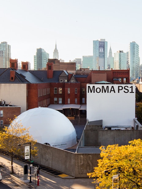 MoMA PS1 exterior with New York City skyline in the background.