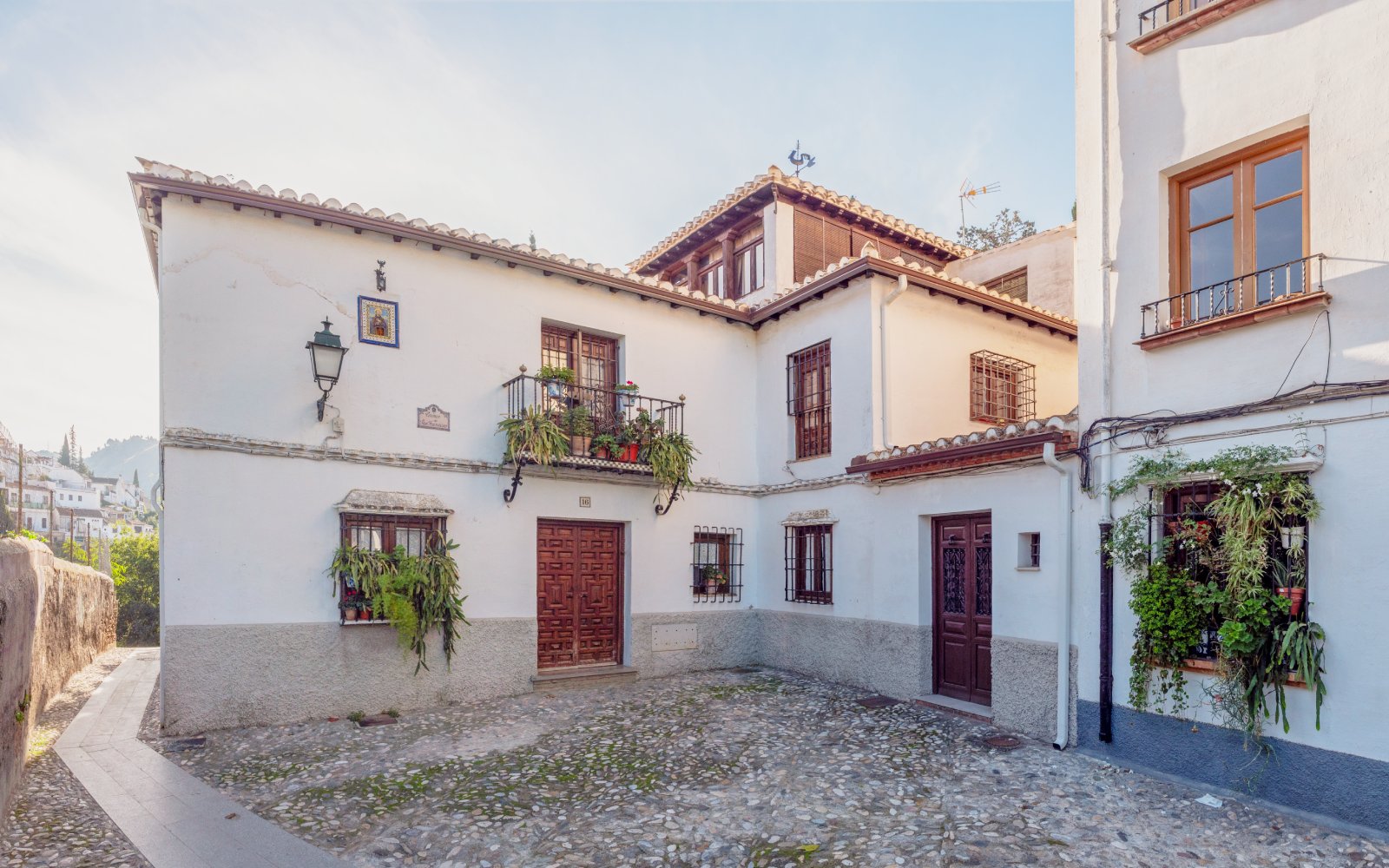 Street in the Albaicin, Granada with flowers on windows at sunset, Spain.