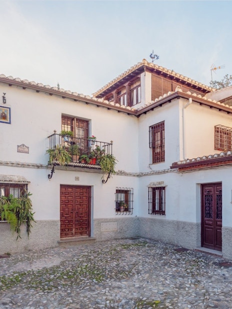 Street in the Albaicin, Granada with flowers on windows at sunset, Spain.