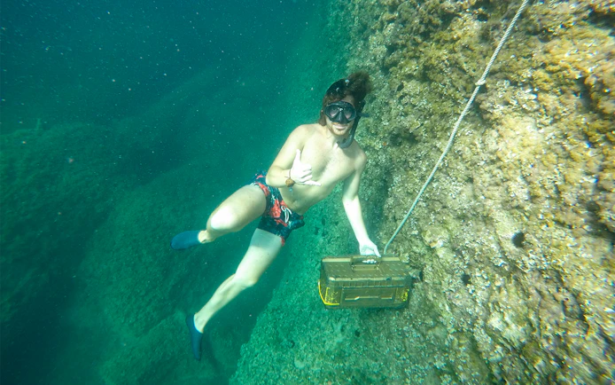 Snorkeler exploring underwater near a rocky sea cave in Mallorca.