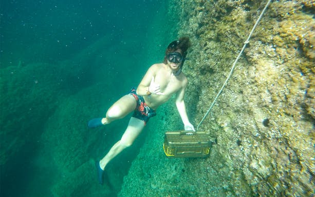 Snorkeler exploring underwater near a rocky sea cave in Mallorca.
