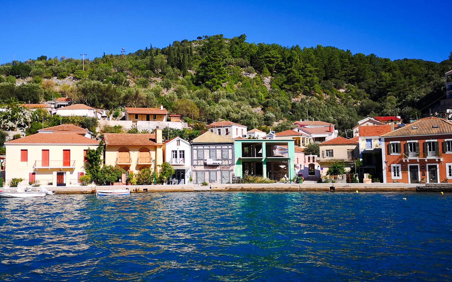 Colorful waterfront buildings in Vathi town, Ithaca, viewed from a cruise in Kefalonia, Greece.