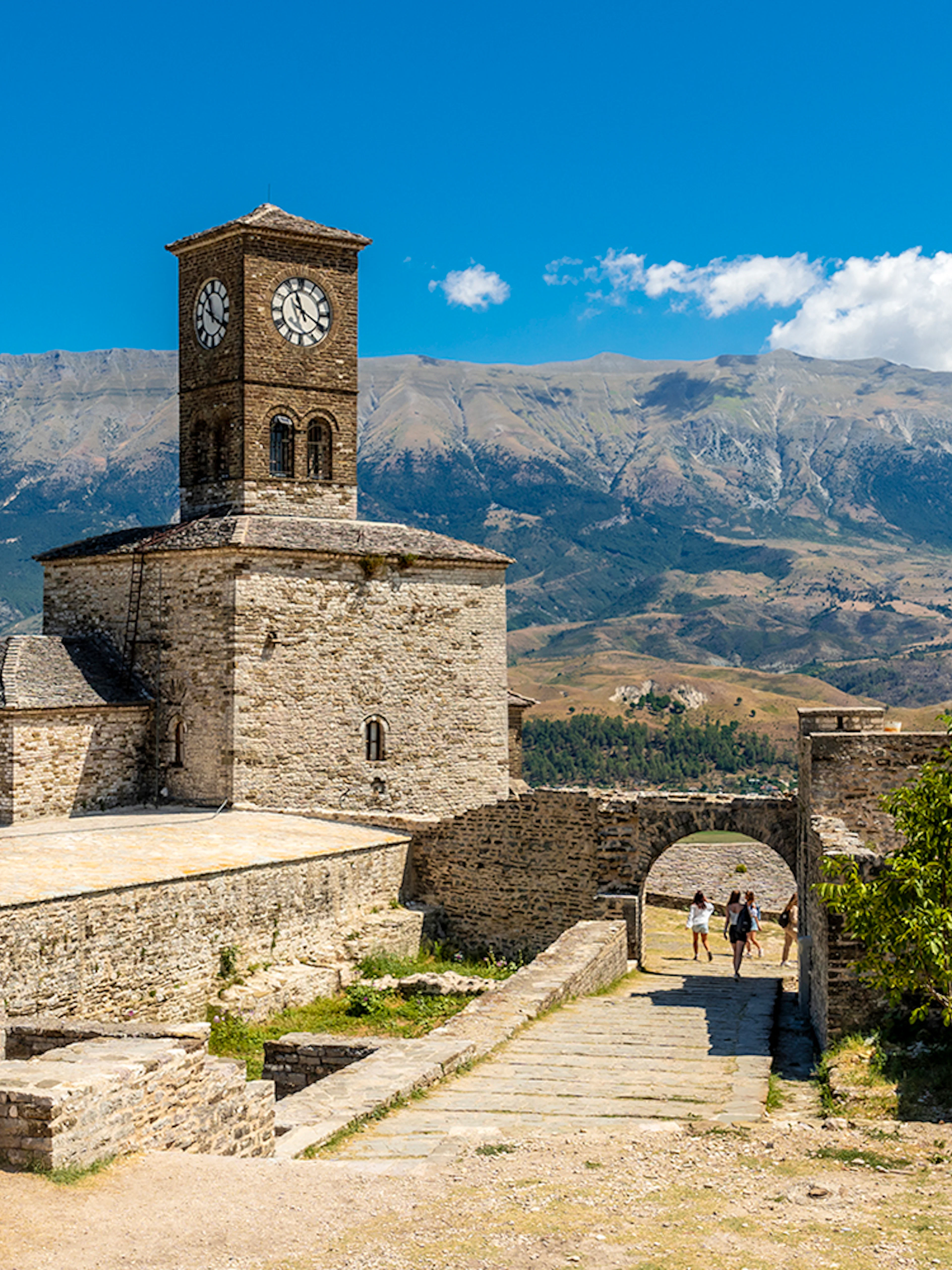 Clock tower in the Ottoman Castle Fortress of Gjirokaster with mountain backdrop.