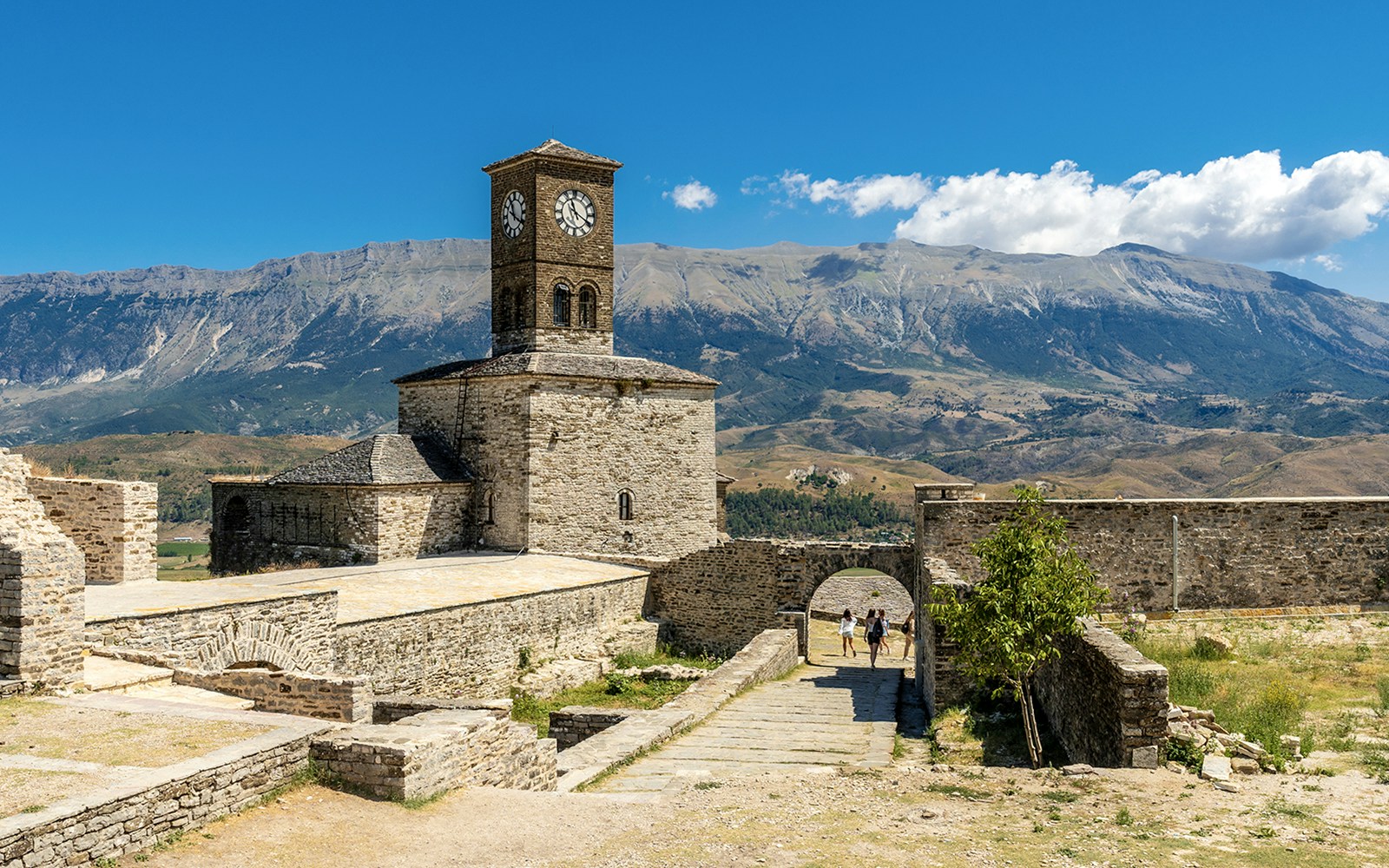 Clock tower in the Ottoman Castle Fortress of Gjirokaster with mountain backdrop.