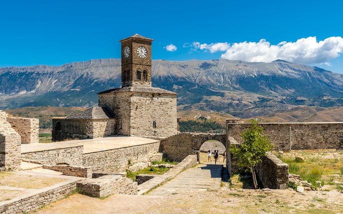 Clock tower in the Ottoman Castle Fortress of Gjirokaster with mountain backdrop.
