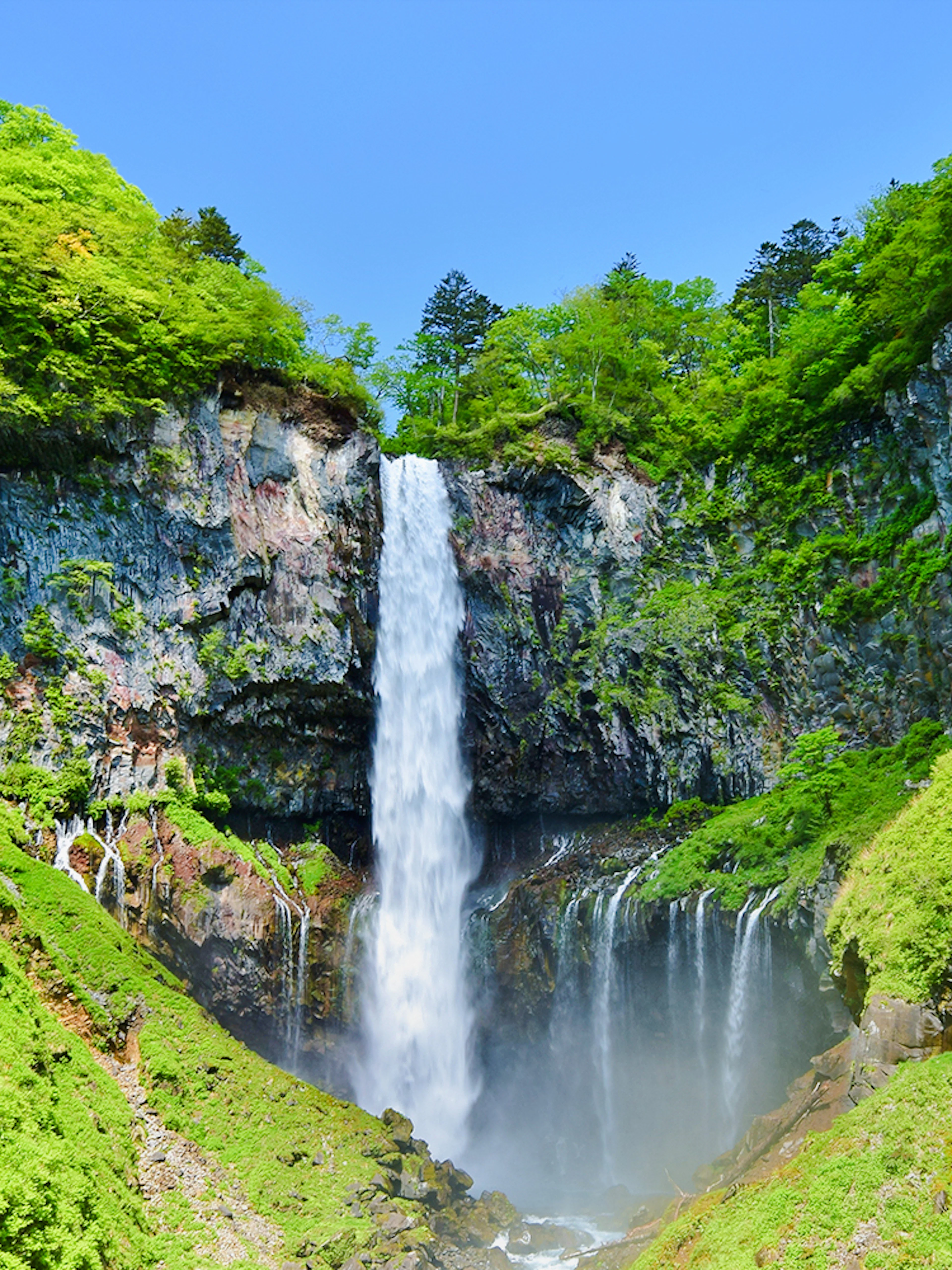 Kegon Falls cascading down a rocky cliff surrounded by lush greenery in Nikko, Japan.