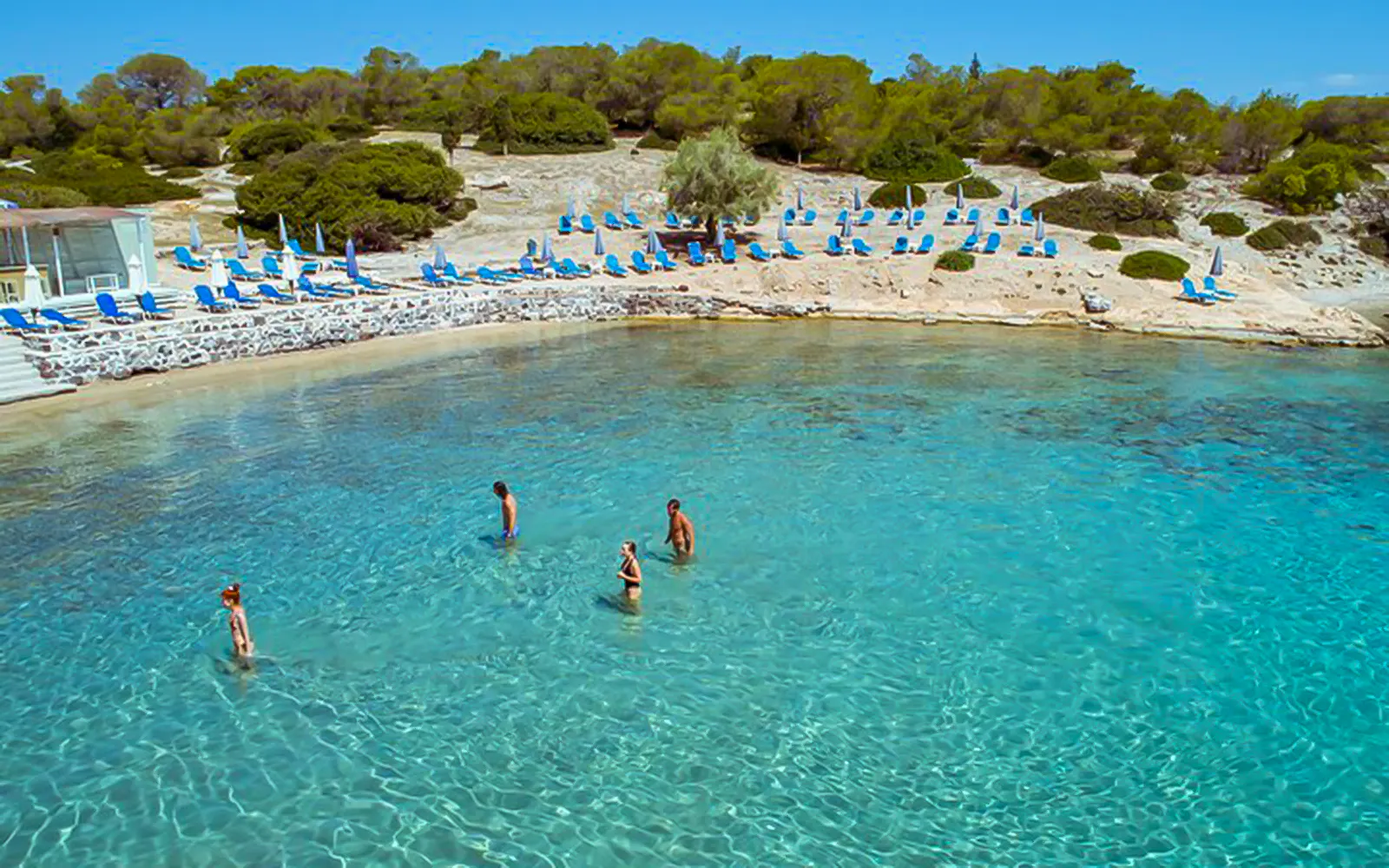 Guests wading in clear water at a beach during Athens Day Cruise.