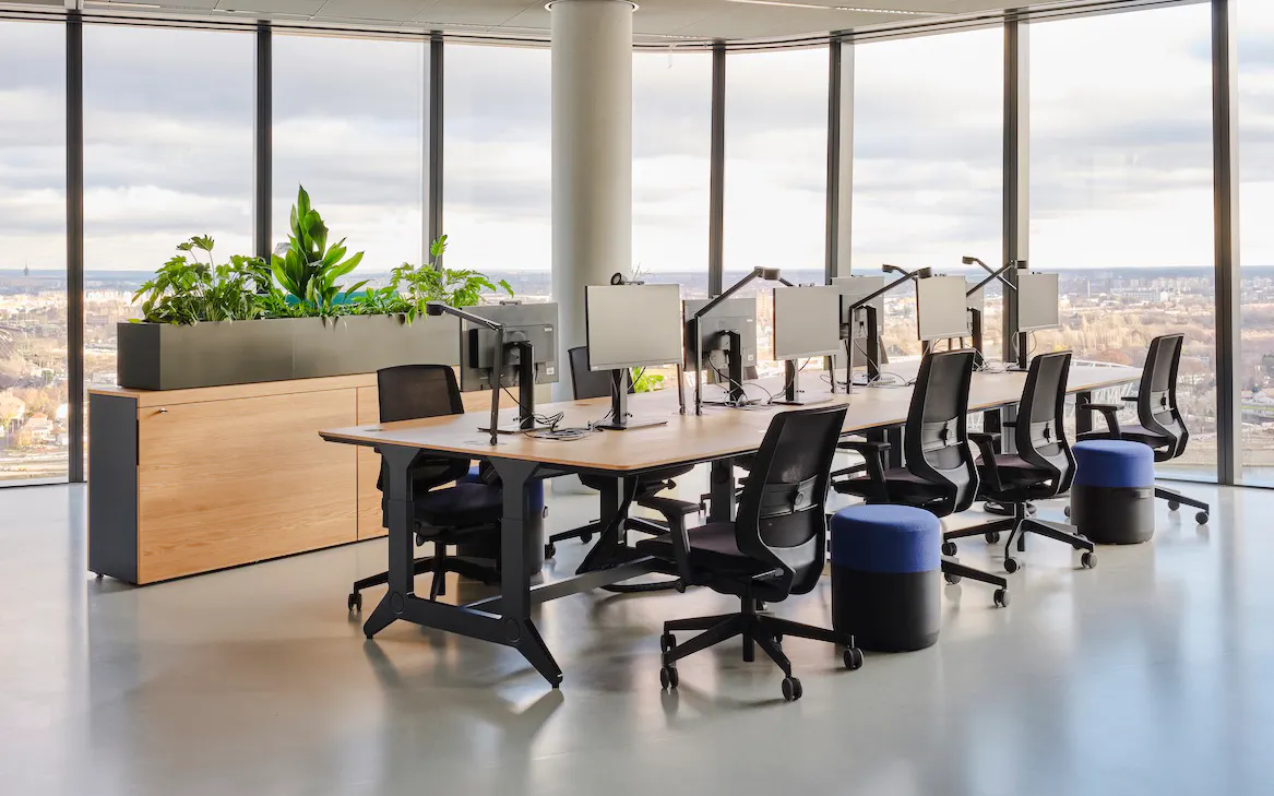 Modern office space with desks and chairs at MOL Campus, featuring large windows and city views.
