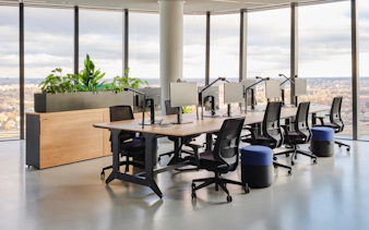 Modern office space with desks and chairs at MOL Campus, featuring large windows and city views.