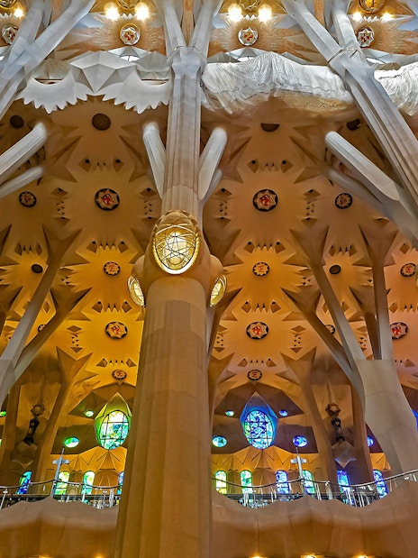Sagrada Familia interior with ornate columns and colorful stained glass windows.