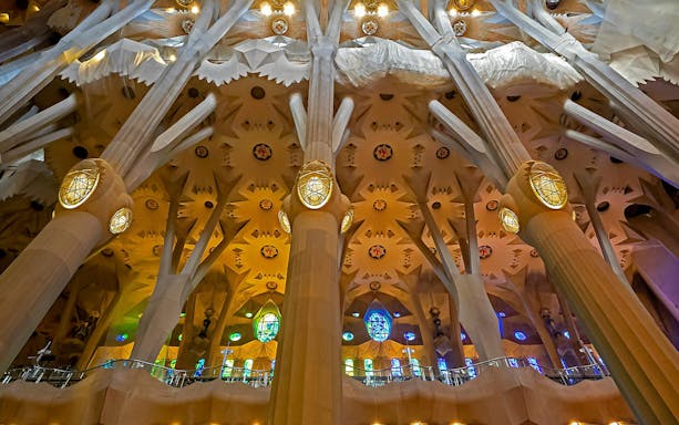 Sagrada Familia interior with ornate columns and colorful stained glass windows.