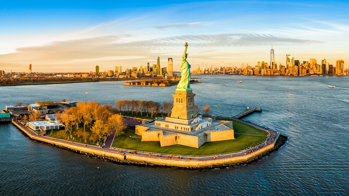 Aerial view of the Statue of Liberty with New York City skyline in the background.
