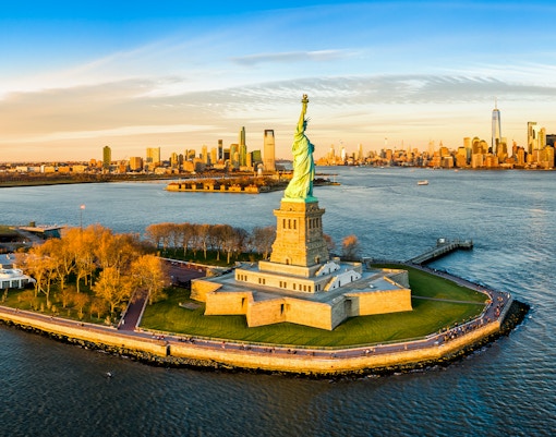 Aerial view of the Statue of Liberty with New York City skyline in the background.