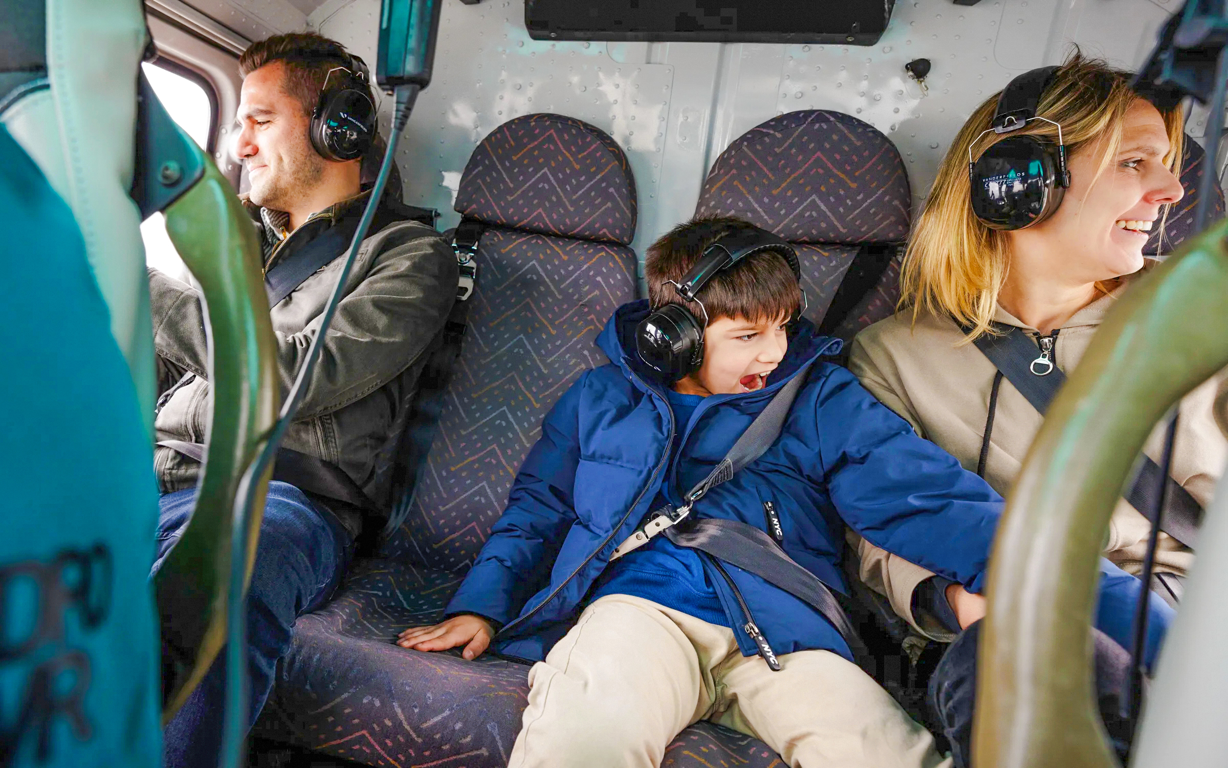Tourists wearing headsets inside a helicopter.