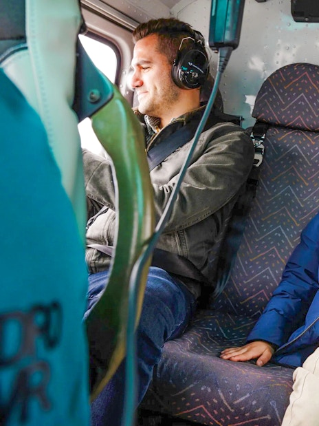 Tourists wearing headsets inside a helicopter.