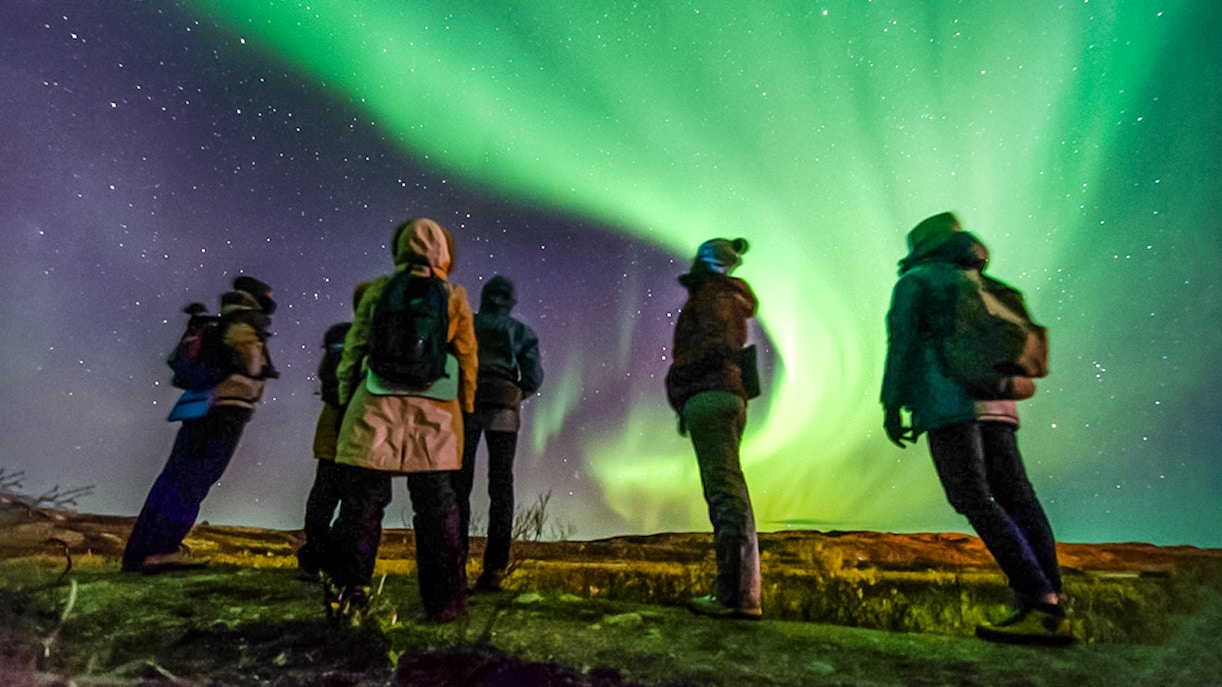 Friends watching Northern Lights in a night sky, Northern Hemisphere.