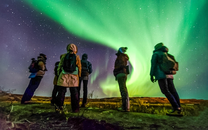 Friends watching Northern Lights in a night sky, Northern Hemisphere.