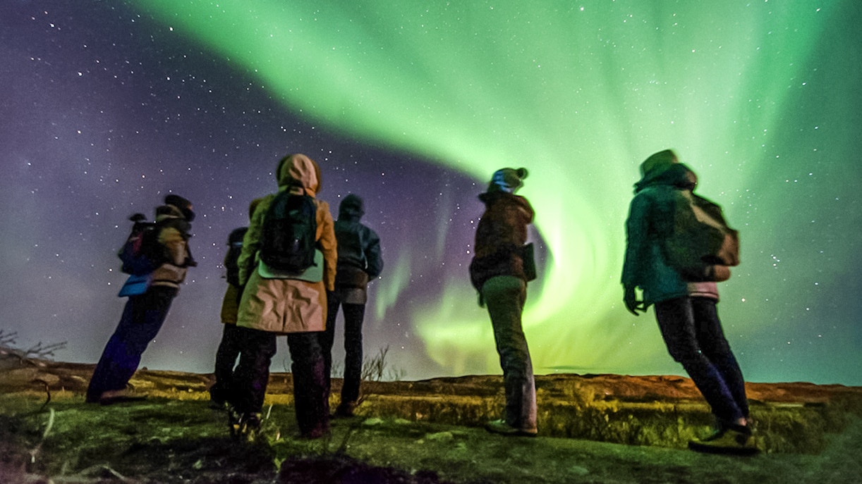 Friends watching Northern Lights in a night sky, Northern Hemisphere.