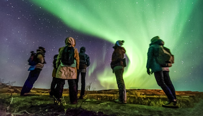 Friends watching Northern Lights in a night sky, Northern Hemisphere.