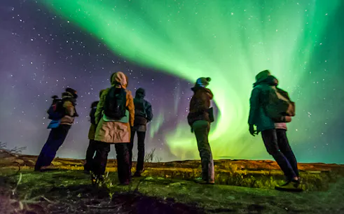 Friends watching Northern Lights in a night sky, Northern Hemisphere.