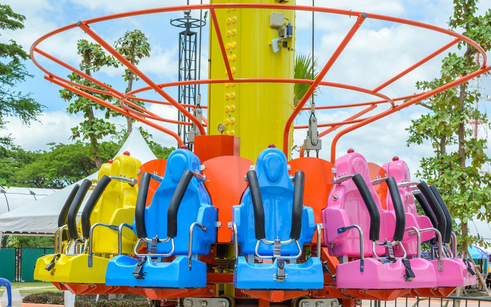 Colorful drop tower ride seats at an amusement park.