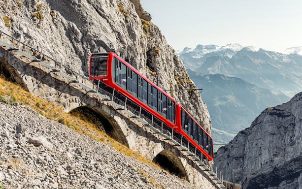 Red train ascending Mount Pilatus on the Pilatusbahn railway, Switzerland.
