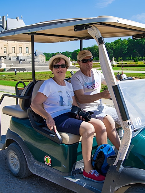 Visitors in a golf cart at Vaux-le-Vicomte, France, with the château in the background.