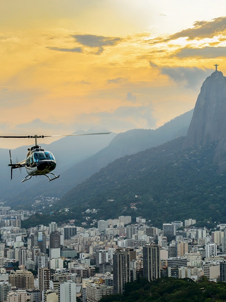 Helicopter flying over Rio de Janeiro with Christ the Redeemer at sunset.