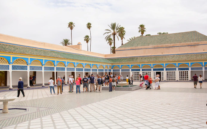 Tourists exploring the courtyard of Bahia Palace in Marrakech.
