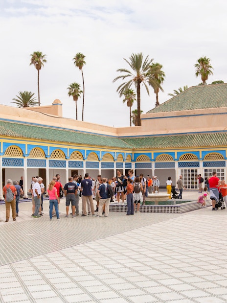 Tourists exploring the courtyard of Bahia Palace in Marrakech.