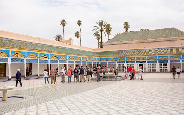 Tourists exploring the courtyard of Bahia Palace in Marrakech.