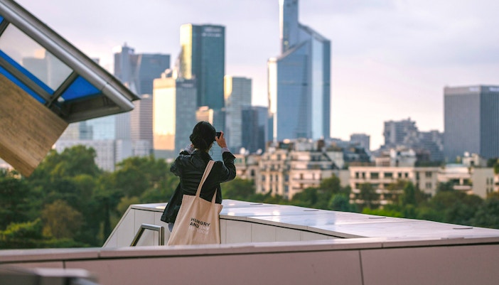 Woman photographing Paris skyline from Fondation Louis Vuitton rooftop.