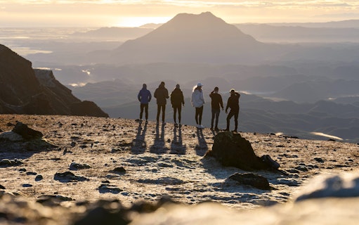 Group of people on a volcanic walk at sunrise, Mount Tarawera, New Zealand.