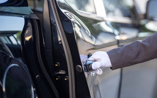Chauffeur opening car door for passengers in Bali, Indonesia.