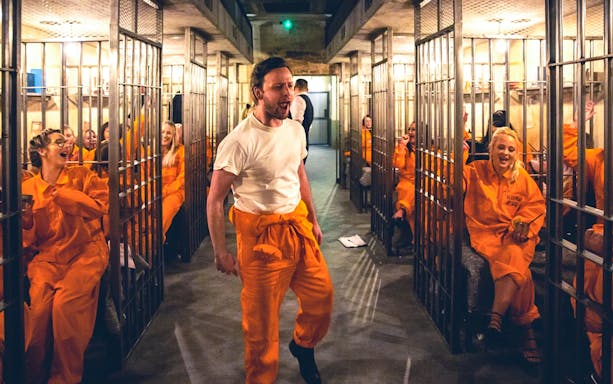 Prison-themed bar with patrons in orange jumpsuits enjoying cocktails, Melbourne.