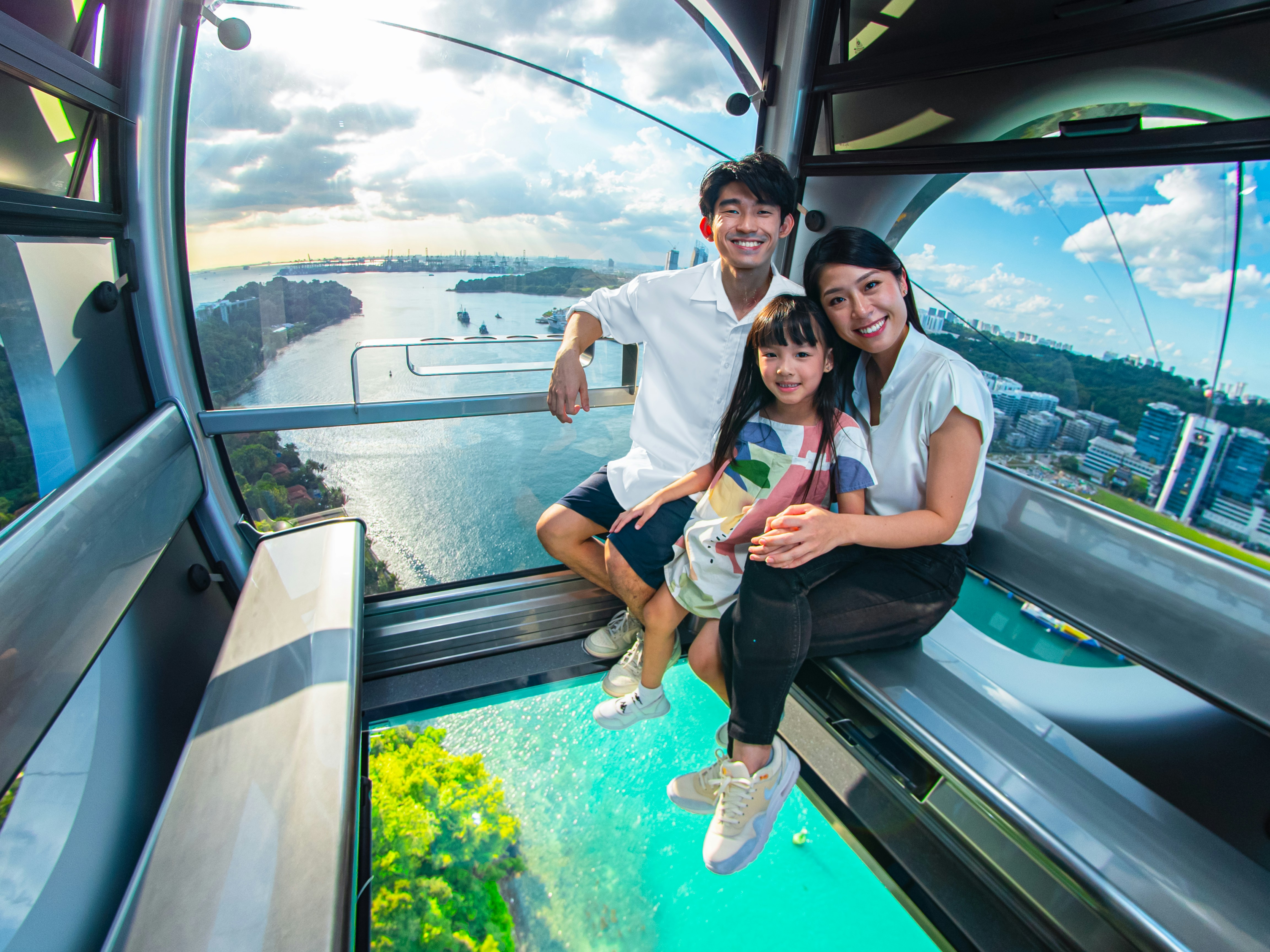 Family enjoying the Sky Orb ride with panoramic city views in the background.