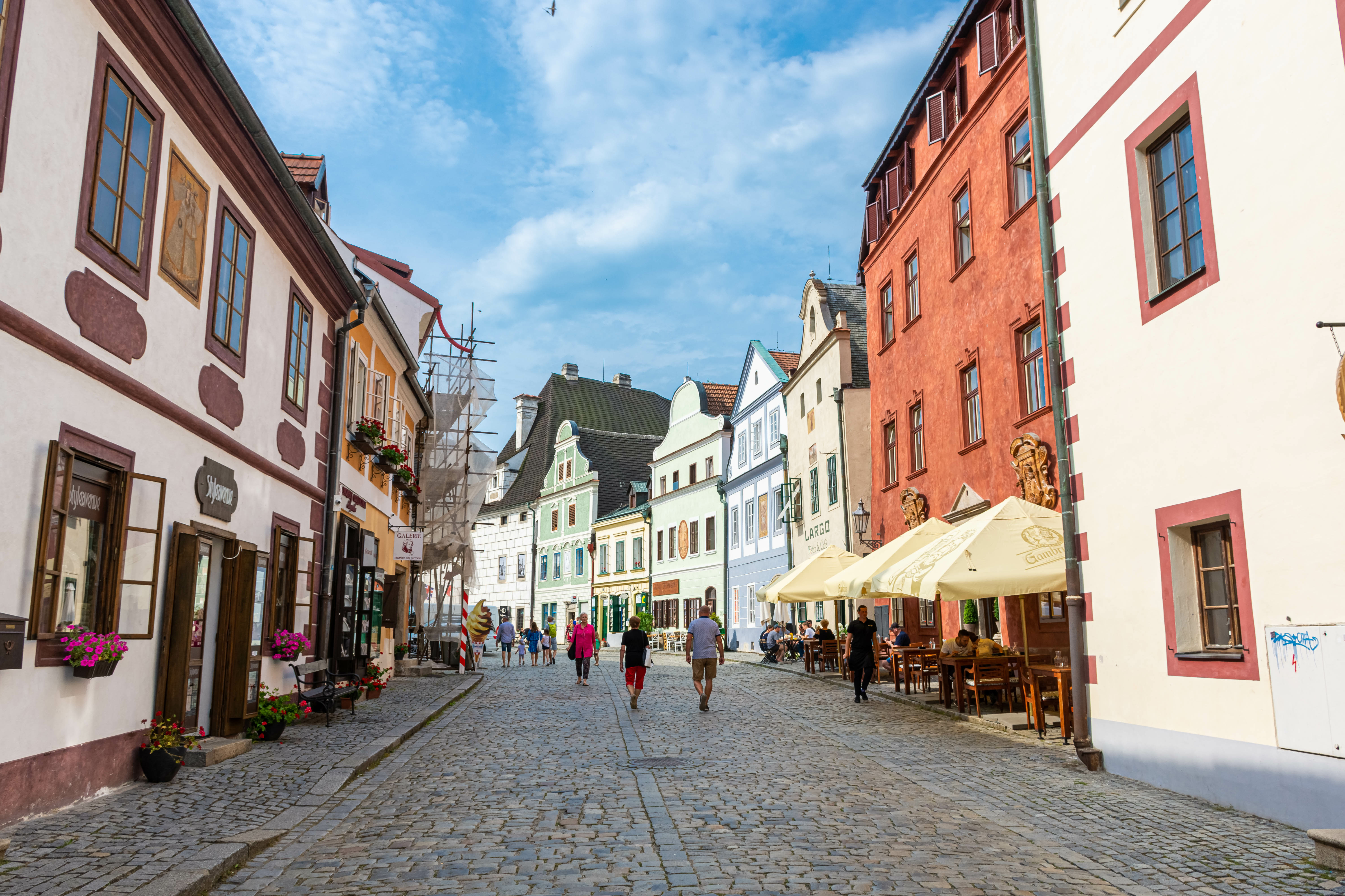 Tourist walking through cobblestone streets of Cesky Krumlov, Czech Republic, with historic buildings in view.