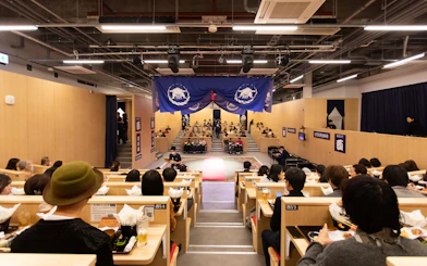 Kyoto sumo show audience dining on chicken hot pot in theater setting.