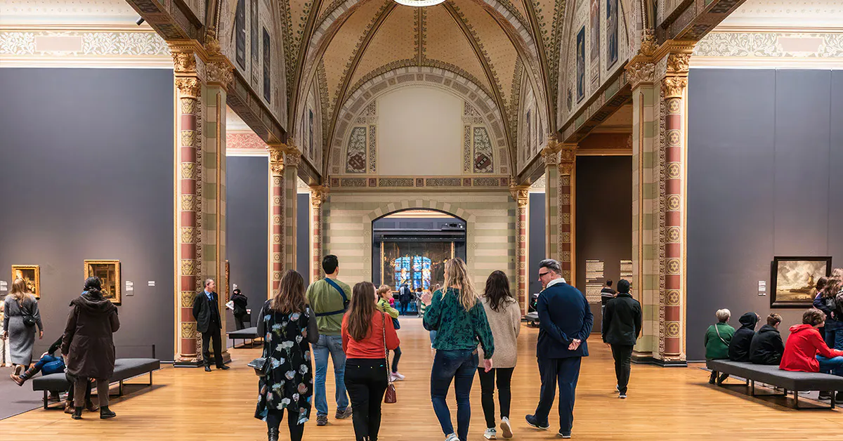 Visitors exploring the Rijksmuseum's ornate gallery during a guided tour in Amsterdam.