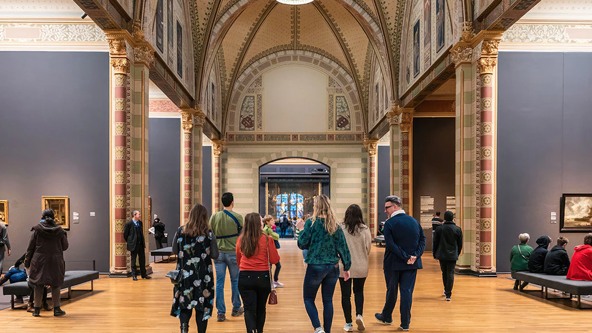 Visitors exploring the Rijksmuseum's ornate gallery during a guided tour in Amsterdam.