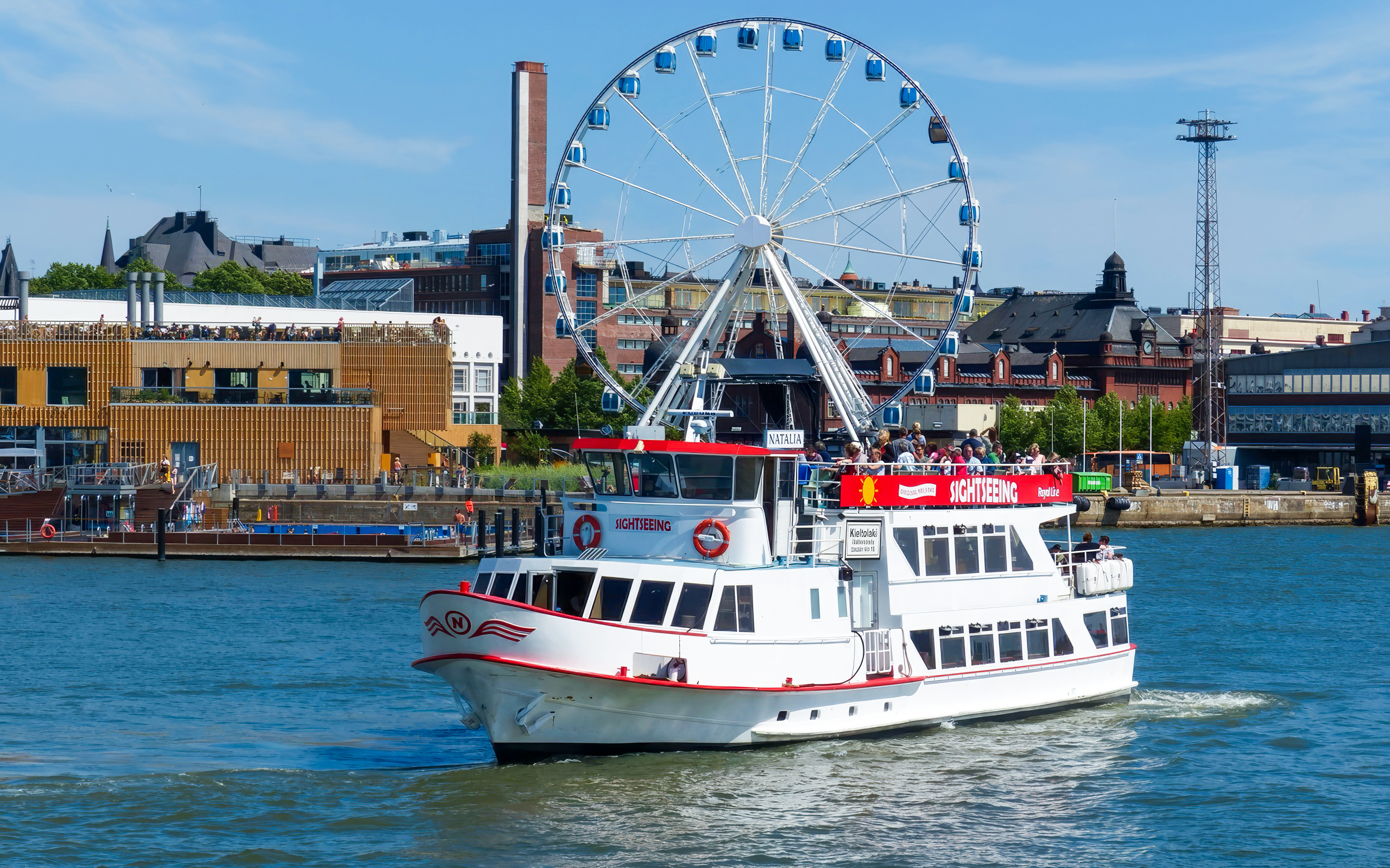 Guests on a sightseeing ship near a Ferris wheel in Helsinki, Finland.
