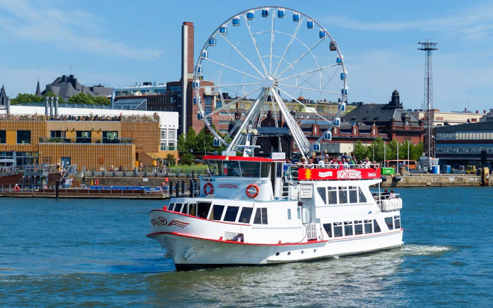 Guests on a sightseeing ship near a Ferris wheel in Helsinki, Finland.
