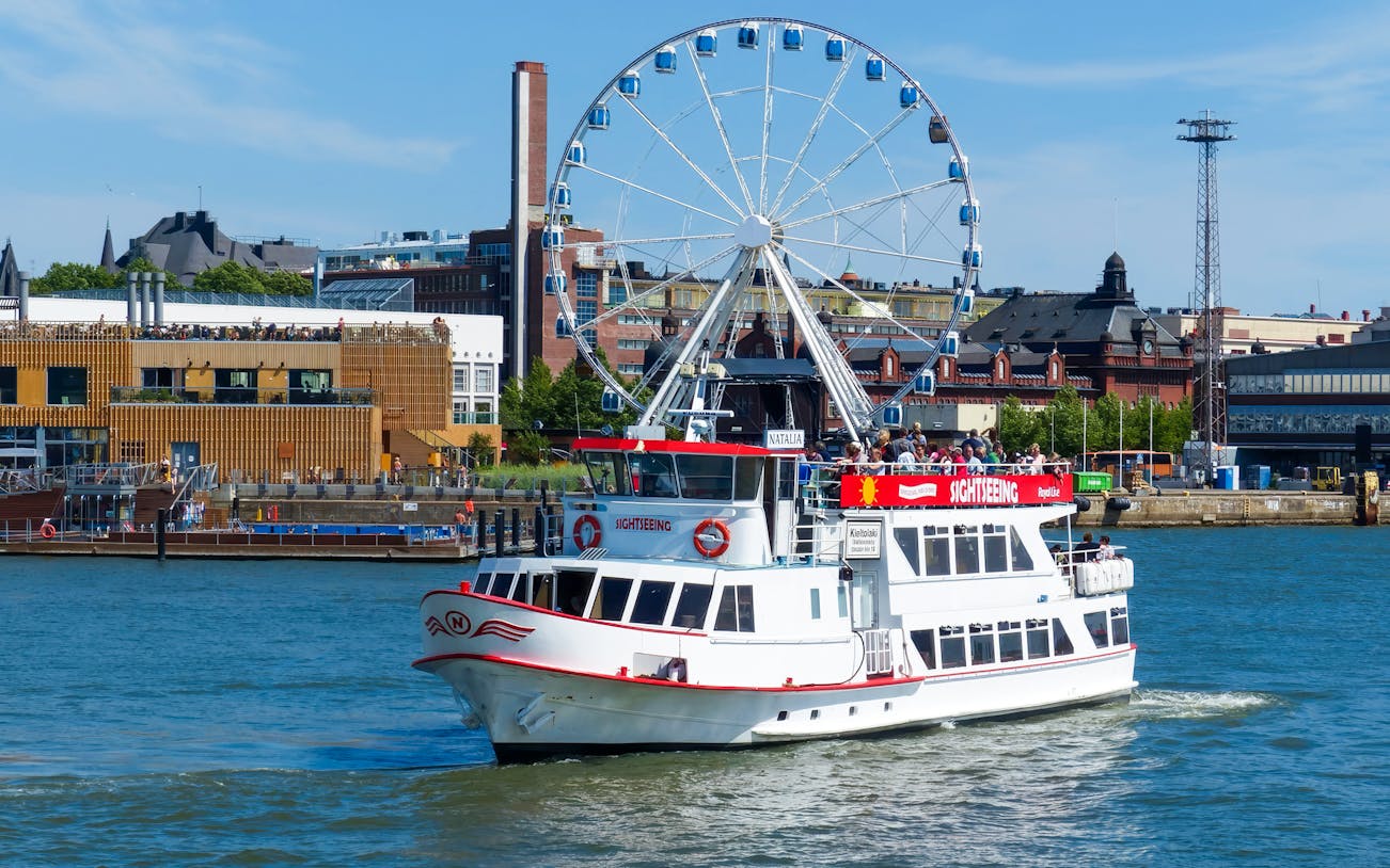 Guests on a sightseeing ship near a Ferris wheel in Helsinki, Finland.