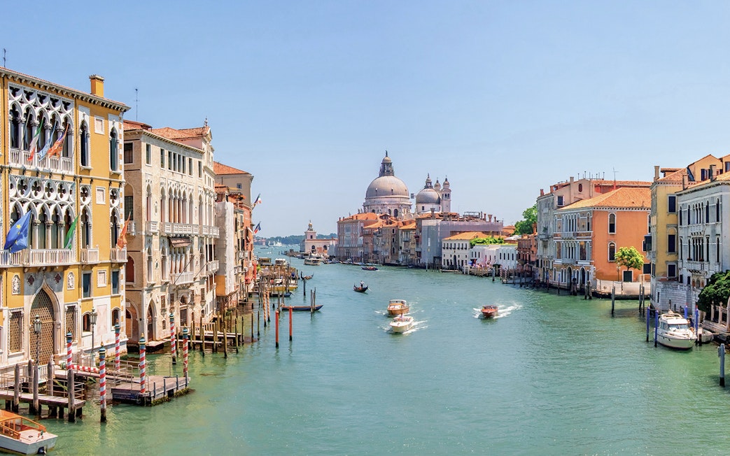 Water bus on Venice Grand Canal with historic buildings and Santa Maria della Salute in the background.